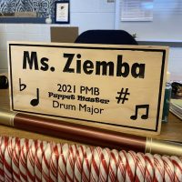 A wooden nameplate that says Ms. Ziemba sits on a desk.