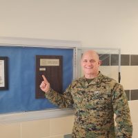 Col Church points to his name on plaque