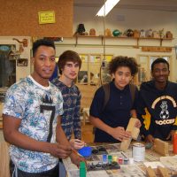 High school students in woodworking classroom posing for photo