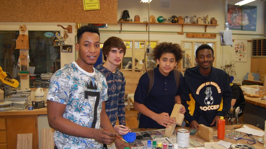High school students in woodworking classroom posing for photo