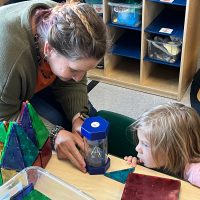 Bucks IU Pre-K Counts Paraeducator; Vicki McGarvey, spends time one-on-one with Finn Kaufmann to examine a sand timer (hourglass) during the class independent exploration period. period.