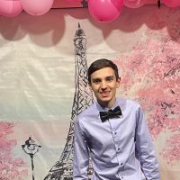 Kaden Wynne poses in front of the Paris themed backdrop at the Prom.