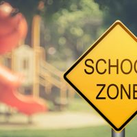 School Zone sign in front of school playground.