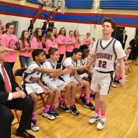 Basketball players participate on the sidelines with cheerleaders behind them at the Coaches vs. Cancer tournament at Maple Point