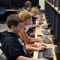 QCHS students sitting side-by-side with computers begin competing in the Esports Club.