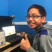 Student gives a thumbs-up while working on a Chromebook